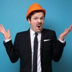 Caucasian young man in orange protective helmet asking what feeling upset