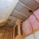 Attic loft insulation partly insulated wall covering view of layers of pink fiberglass barrier